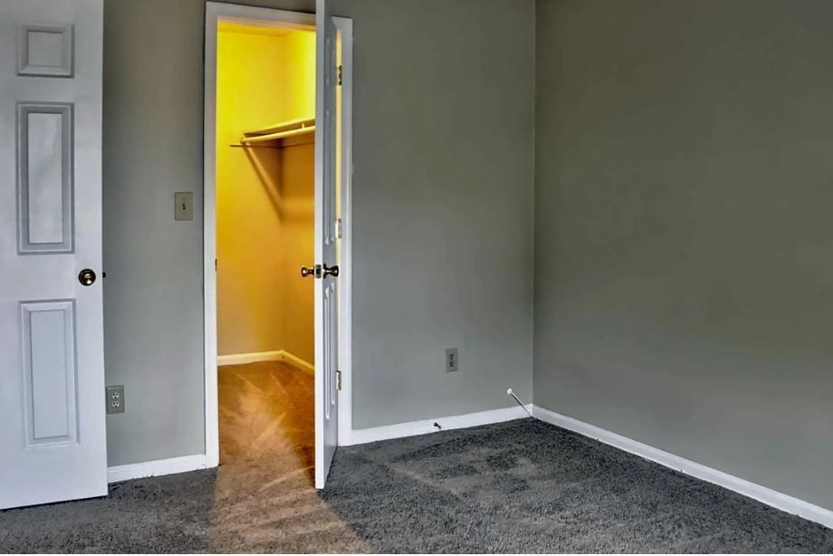 An empty bedroom with a walk in closet in the corner