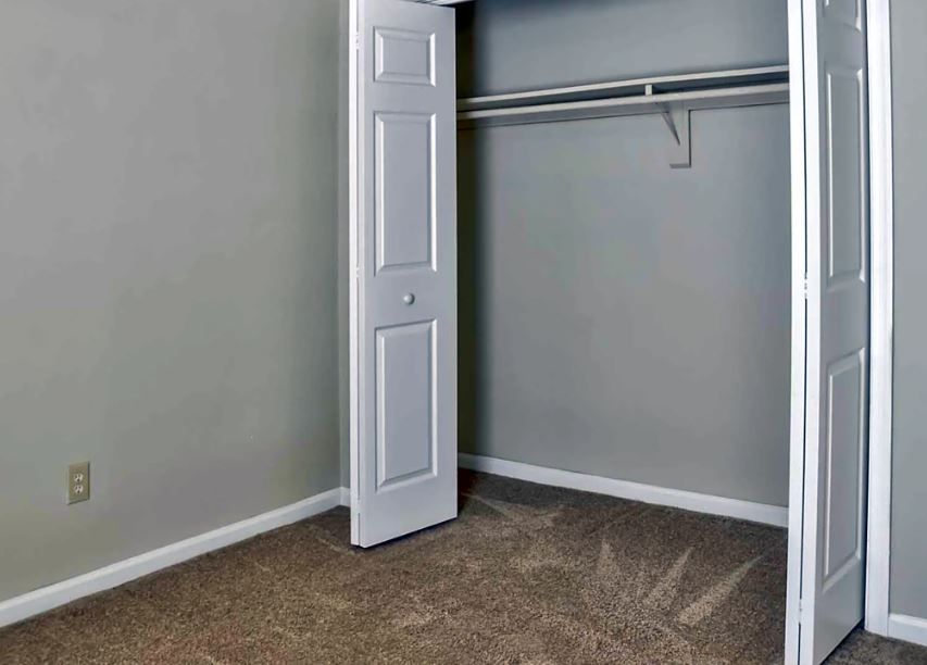 An empty bedroom with a closet and a carpeted floor.