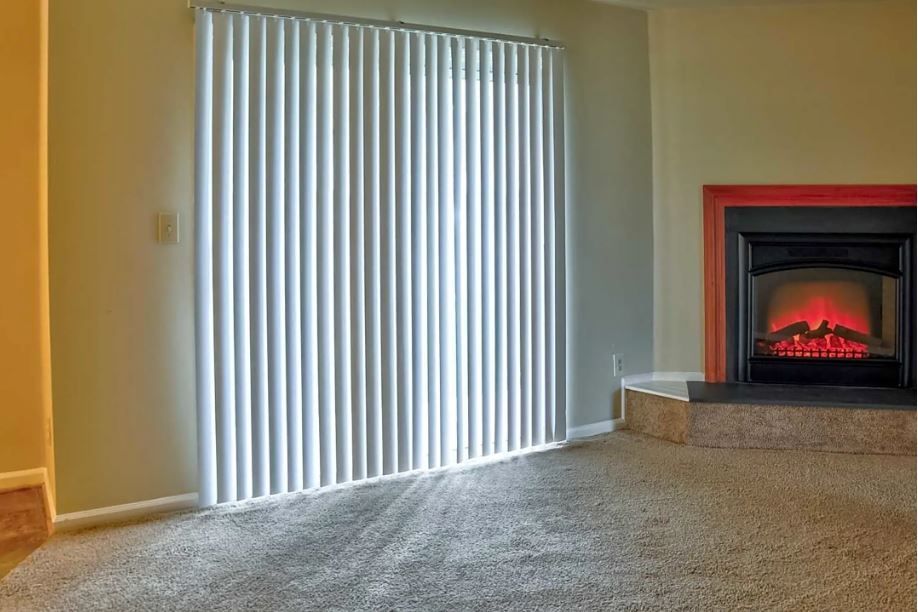 An empty living room with a fireplace and sliding glass doors.