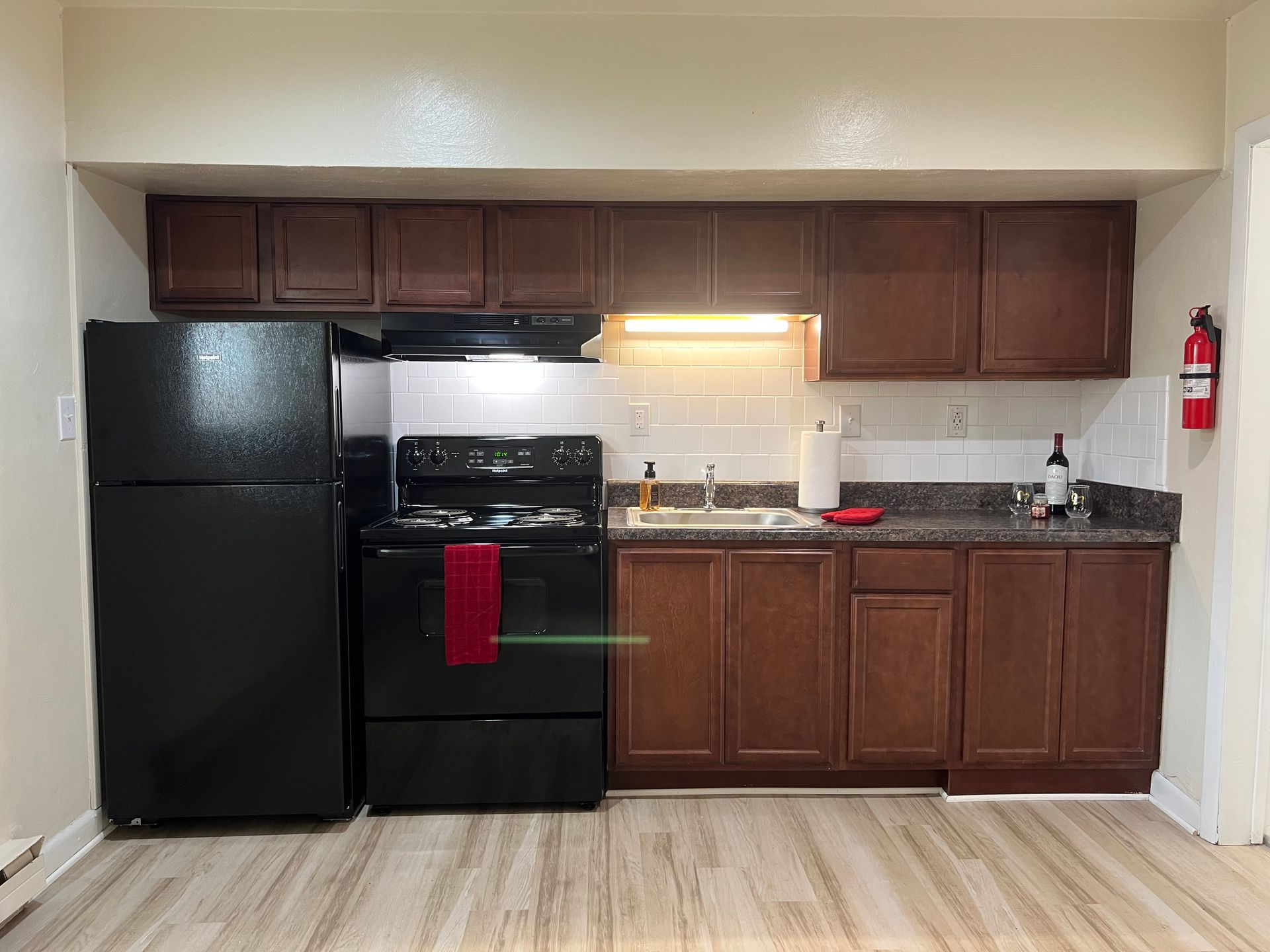 A kitchen with a black refrigerator , stove , sink and cabinets.