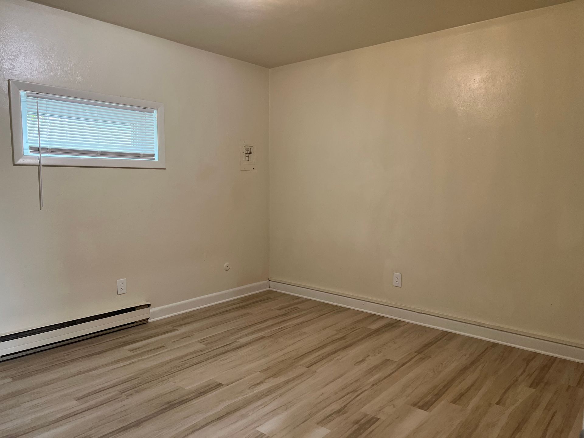 An empty bedroom with hardwood floors and a window.