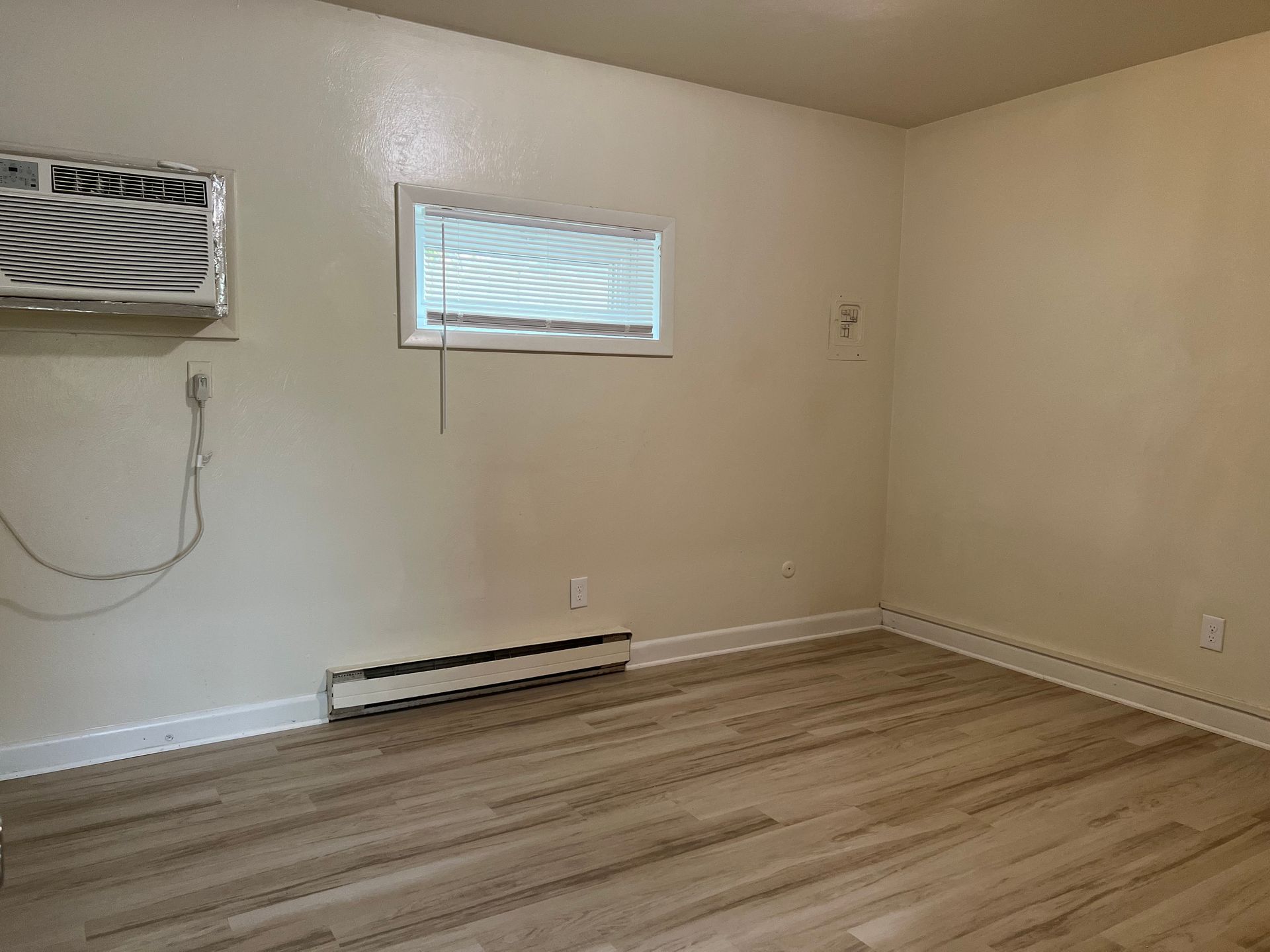 An empty room with a window and air conditioner.