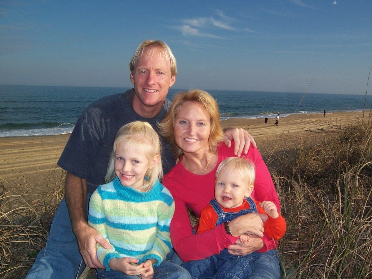 A family is posing for a picture on the beach.