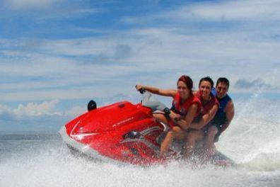 A group of people are riding a red jet ski in the ocean.