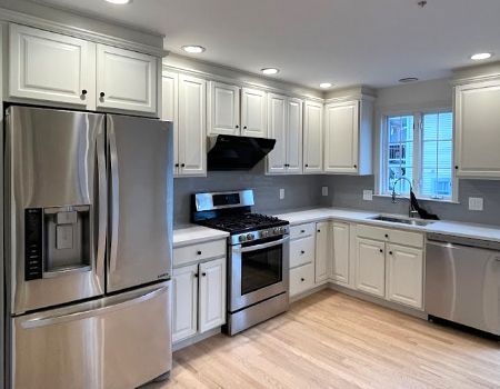 A kitchen with stainless steel appliances and white cabinets.