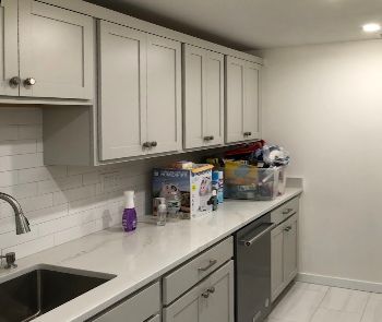 A kitchen with white cabinets , a sink , and a dishwasher.