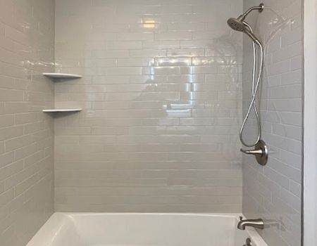 There is a bathtub in the shower with a shower head.