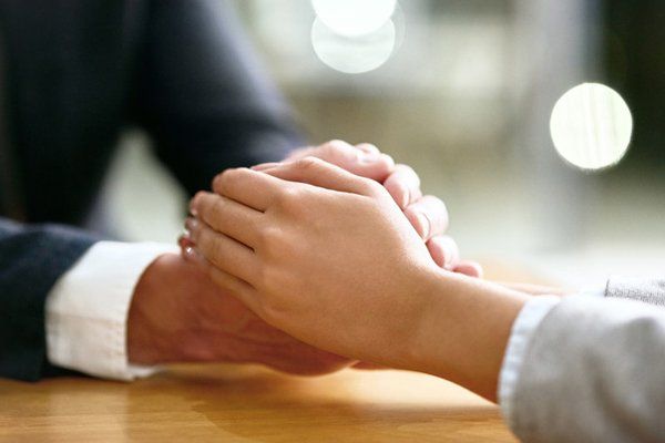 Cropped shot of a businessman and businesswoman compassionately holding hands at a table