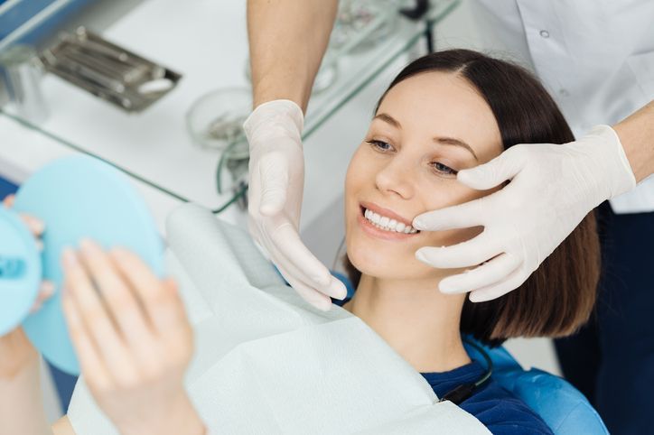 Person getting teeth whitened at a dental clinic. A dental professional operates the whitening machine.