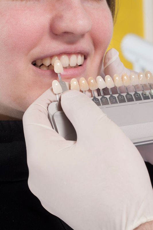 Dentist in blue gloves holding a model of teeth, wearing a stethoscope.