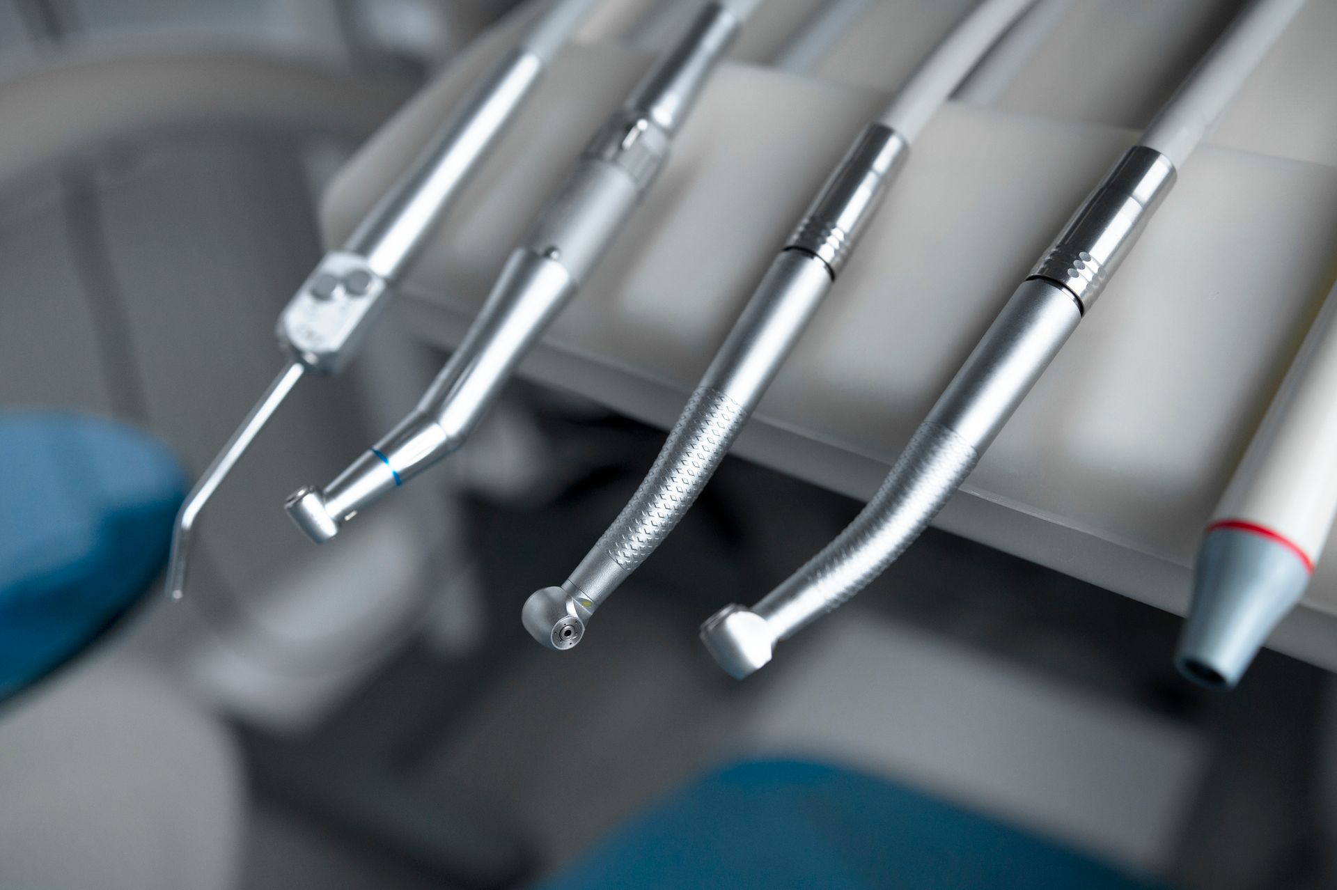 Dental tools on a tray, close-up view of metal instruments with white and gray details.