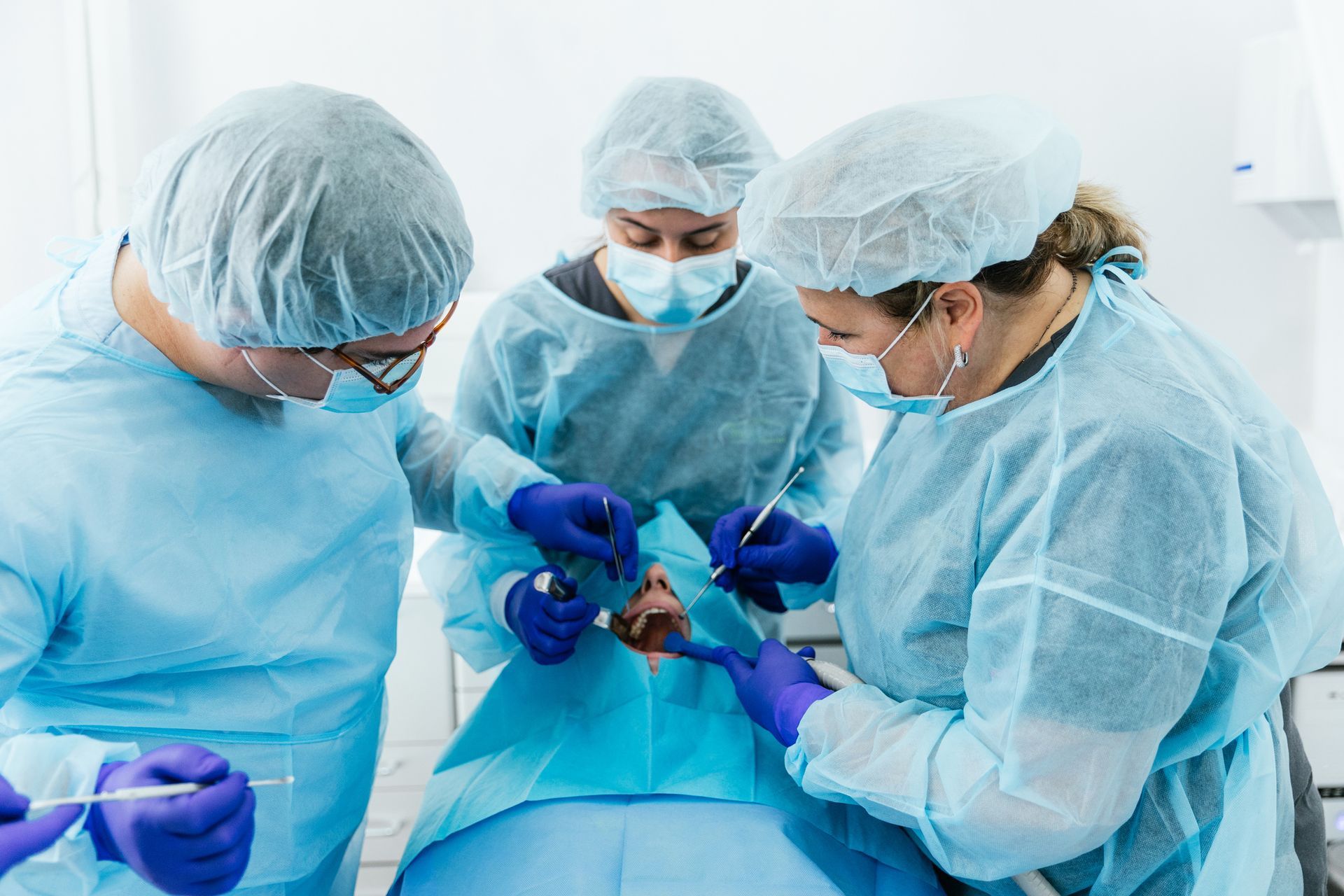 Medical team performing surgery on a patient's face. Operating room. Blue surgical attire.