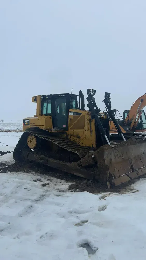Yellow bulldozer on a snowy work site, viewed from the front-left side.