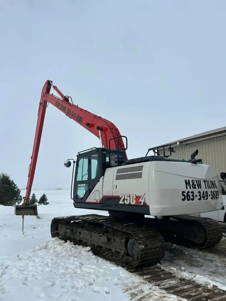Red and white excavator on tracks in a snowy industrial yard
