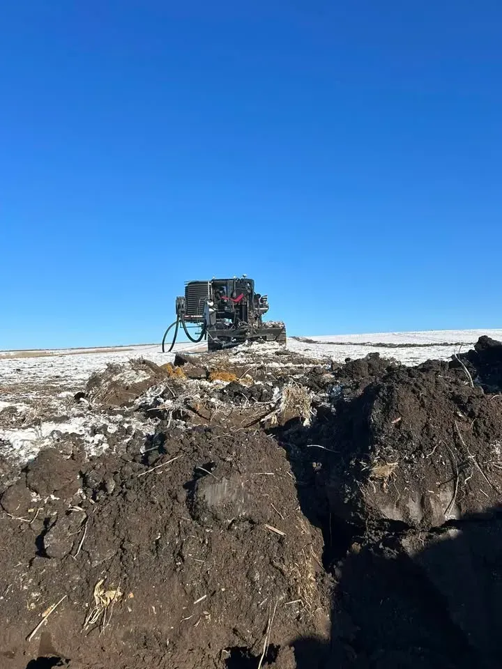 Large machine on a snowy plateau beside a deep dark crevice under a clear blue sky