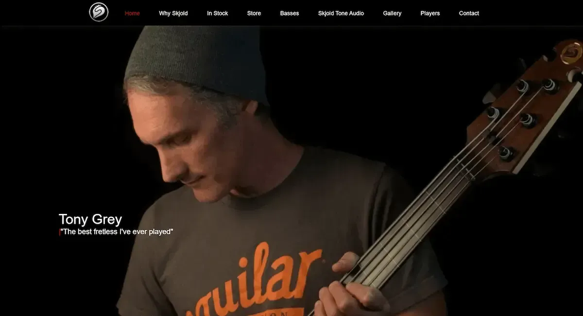 A man wearing a guitar shirt is playing a bass guitar