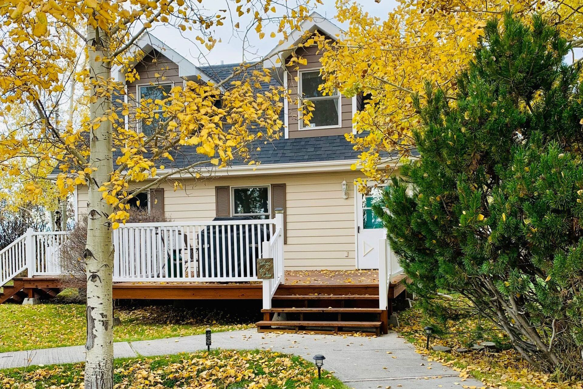 A house with yellow leaves on the trees in front of it.