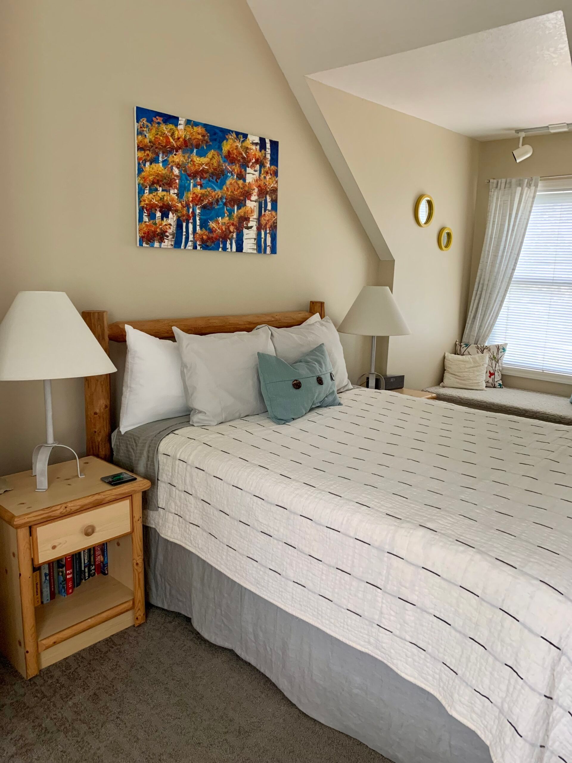 A bedroom with a bed , nightstand , lamp and painting on the wall