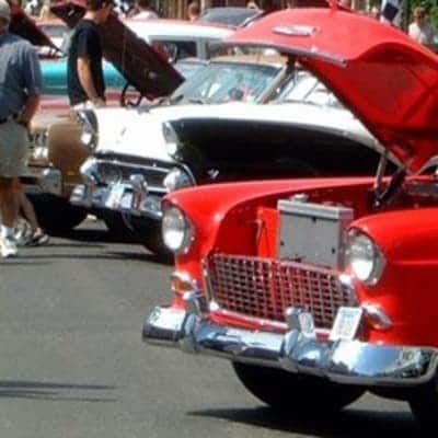 A red car with the hood open is parked next to a white car