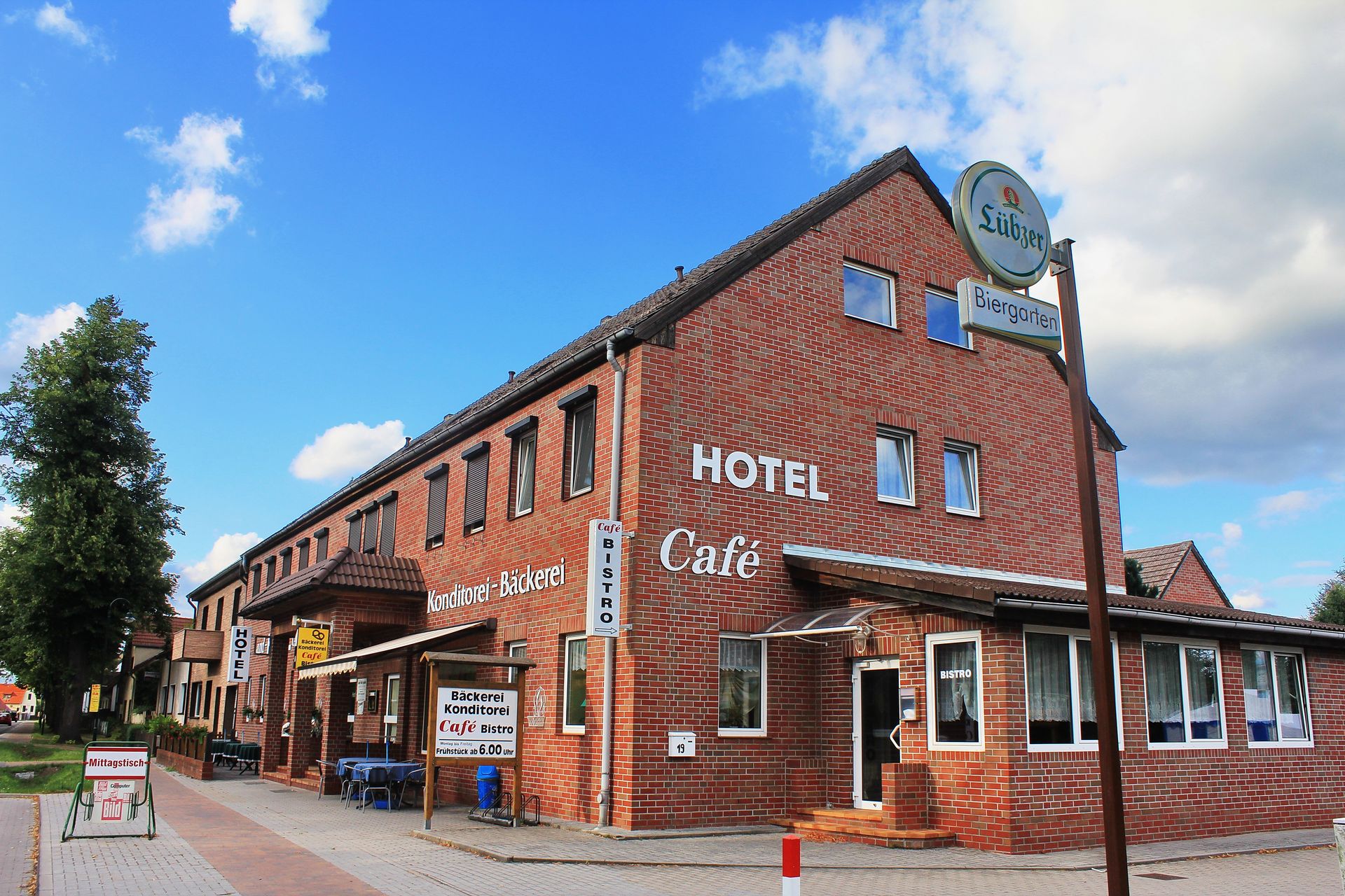 Backsteinhotel und Café, blauer Himmel, Schild mit der Aufschrift „HOTEL“ sichtbar.