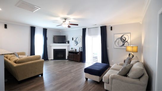 A living room with a couch , chair , ottoman , fireplace and television.