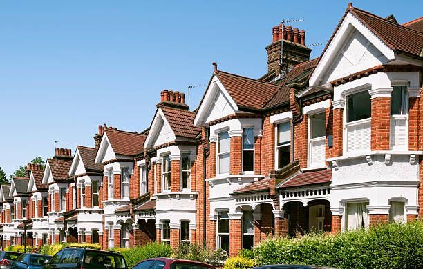 A row of houses with cars parked in front of them on a sunny day.