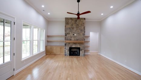 An empty living room with a fireplace and a ceiling fan.