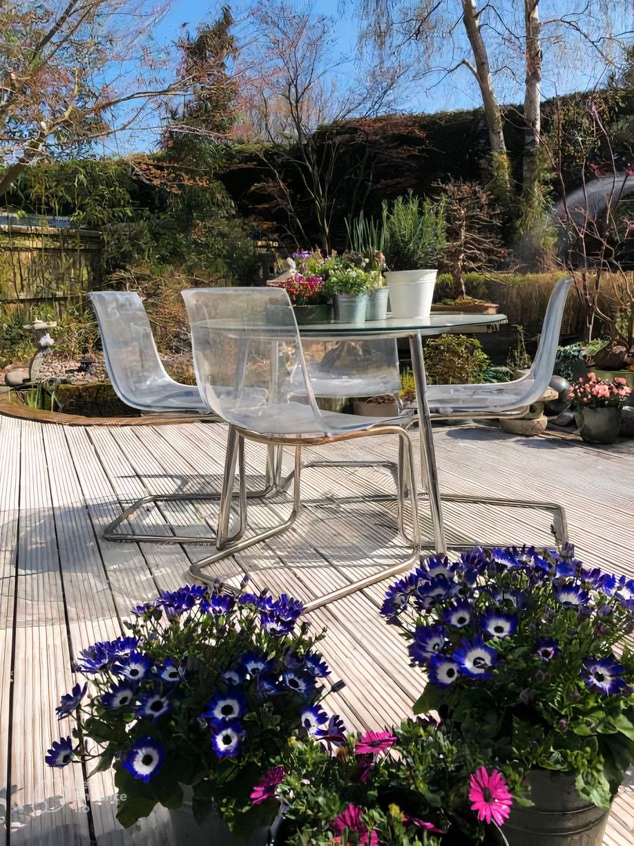 A patio with a table and chairs and potted flowers.