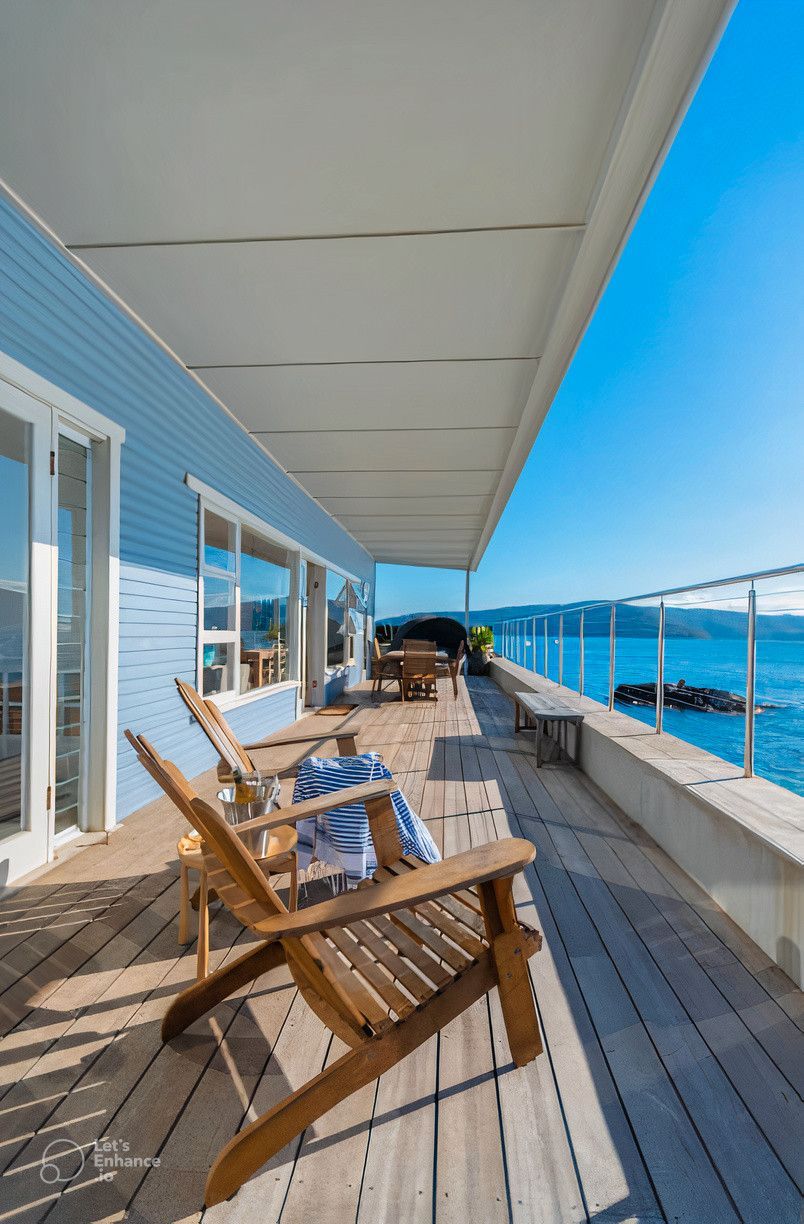 A wooden deck with chairs and a view of the ocean