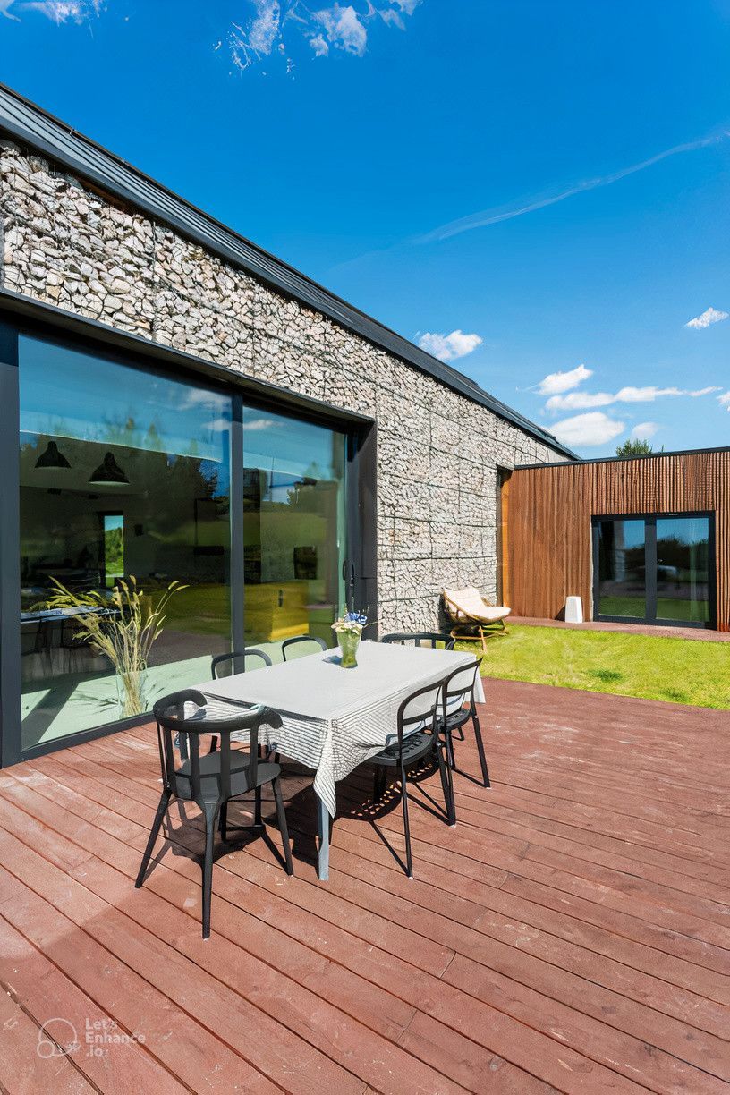 There is a table and chairs on the deck in front of the house.