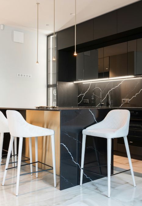 A kitchen with black cabinets and white stools