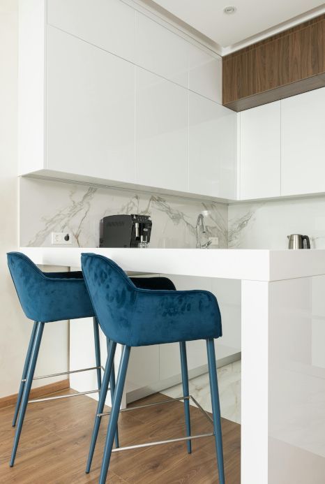 Two blue bar stools are sitting next to a white counter in a kitchen.