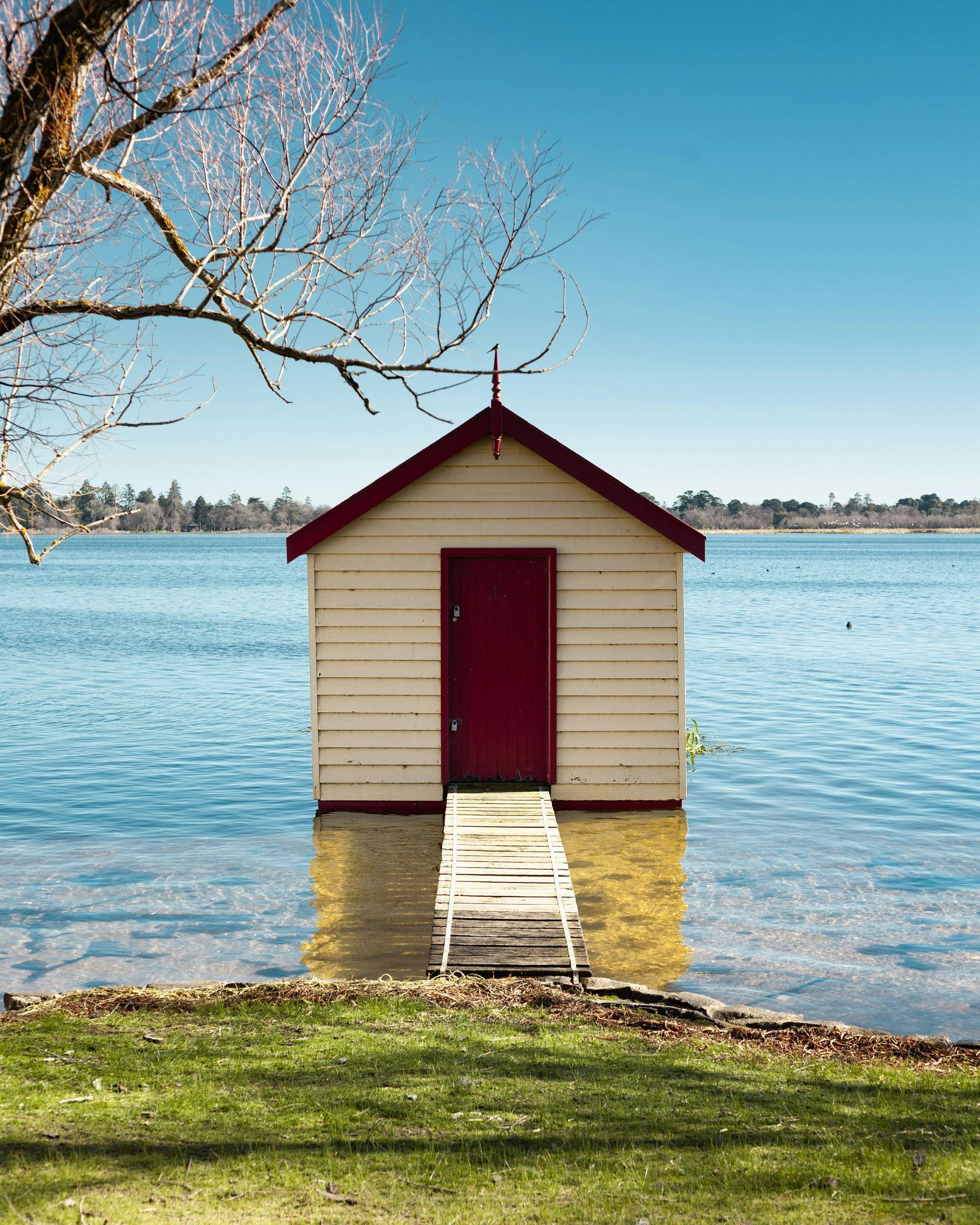 Soft white painted shed on the water in Newport, Wales. Expertly painted using waterproof and wind-resistant wood preserving paint by Orchid Decor.