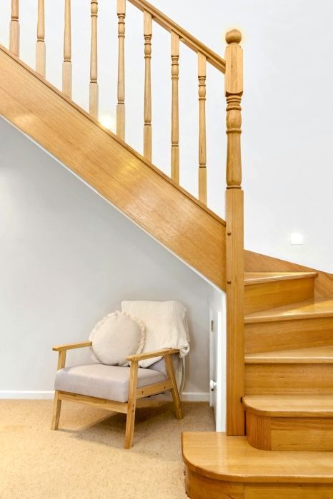 A wooden staircase with a chair underneath it. Expertly varnished by Orchid Decor in Newport, Wales.