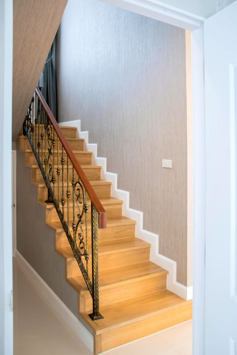 A wooden staircase with a wrought iron railing in a house. Expertly varnished by Orchid Decor in Newport, Wales.