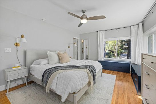 A studio couch with a quilt, four-poster bed, sliding door, and window shade.