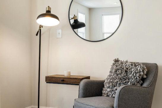 A studio couch near a washbasin, medicine chest, toilet seat, and table lamp.