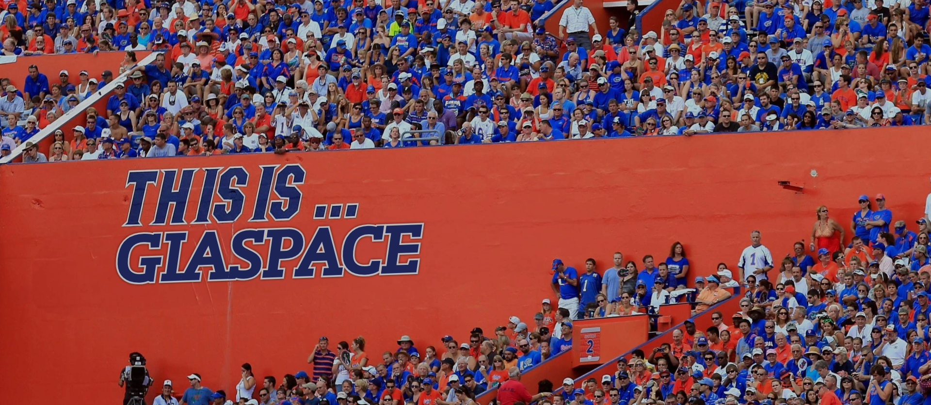 A large crowd of people in Ben Hill Griffin Stadium with writing that says 