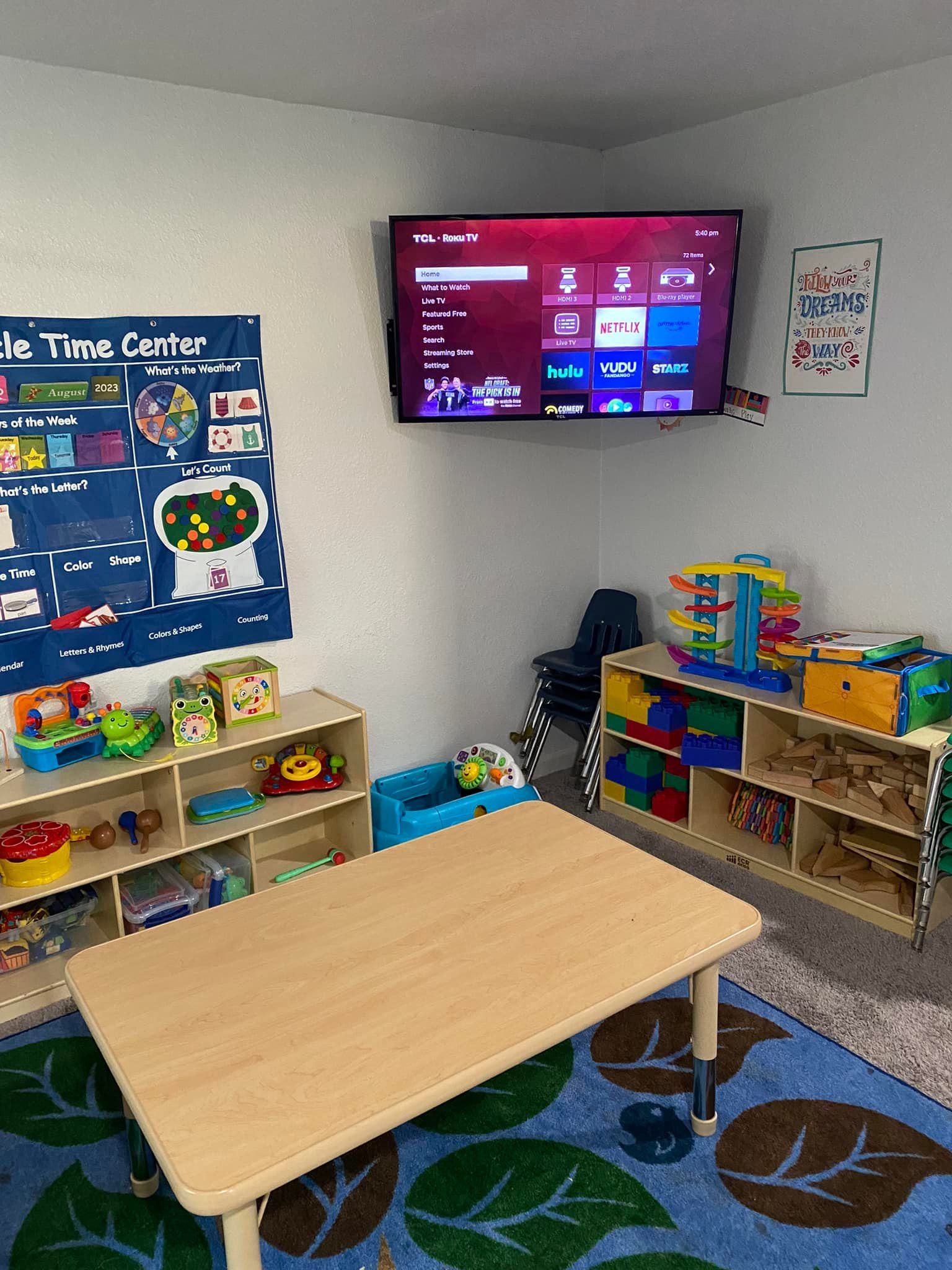 A room with a table , shelves , and a flat screen tv.