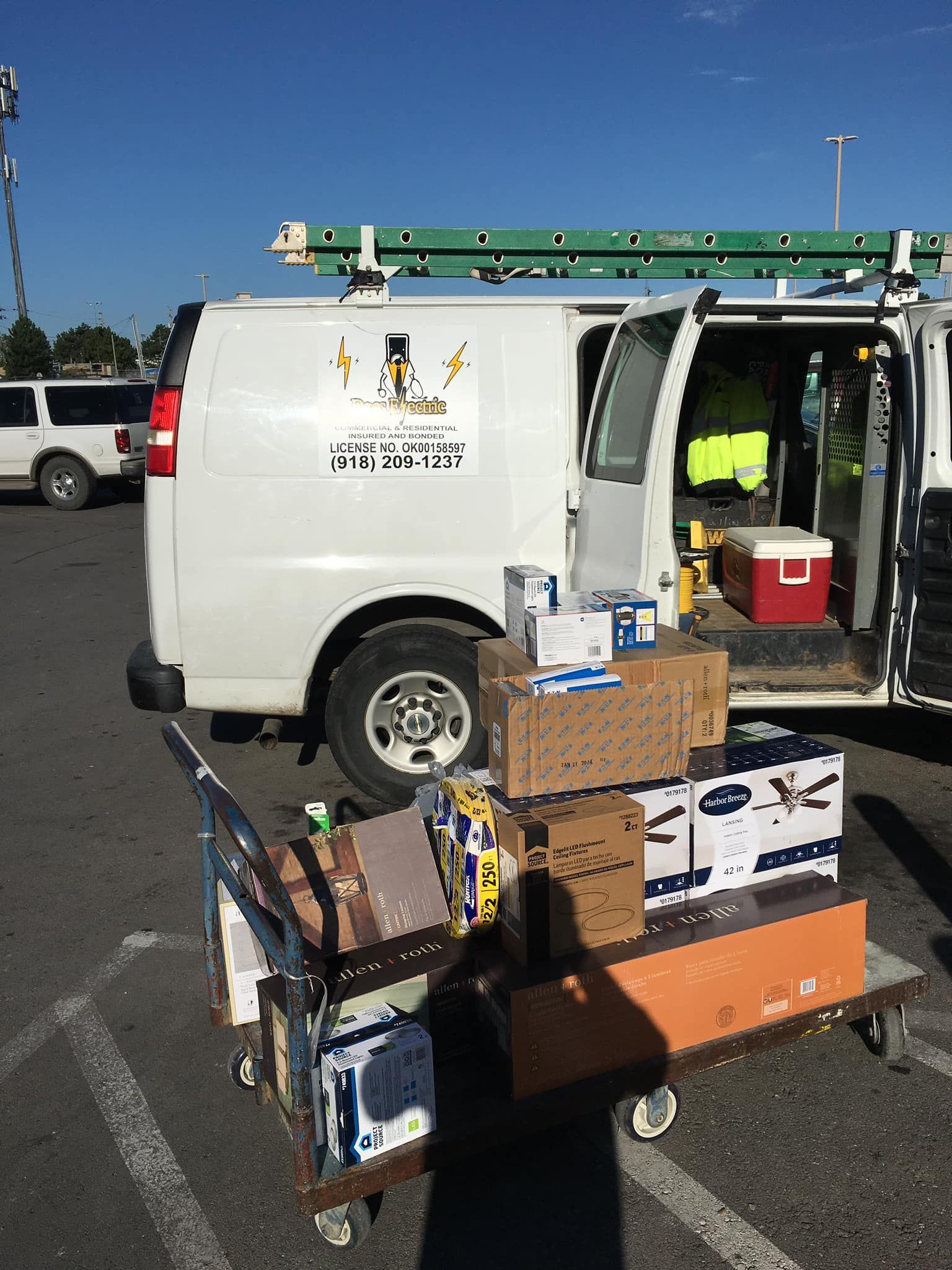 A white van is parked in a parking lot with boxes in the back.