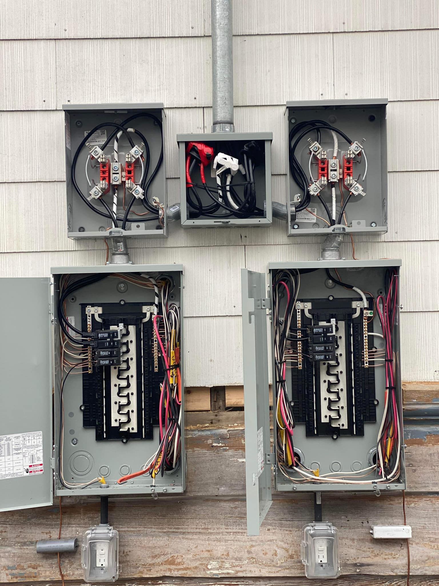 Two electrical boxes are sitting on the side of a building.