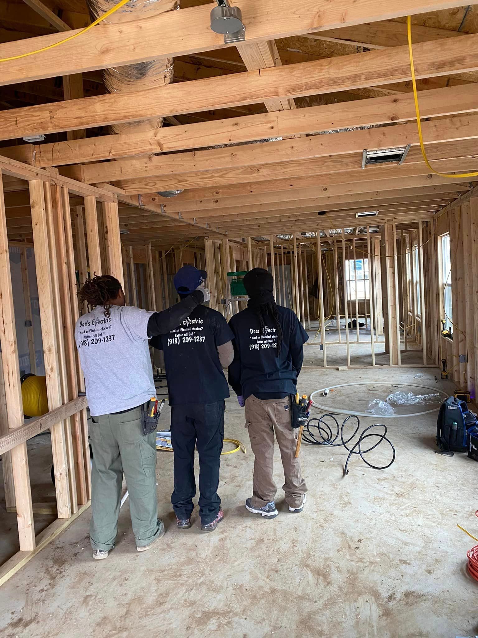 A group of construction workers are standing in a room under construction.