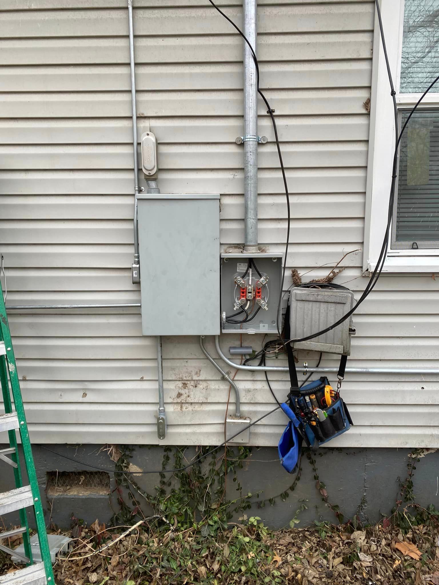 A ladder is sitting next to a box on the side of a house.