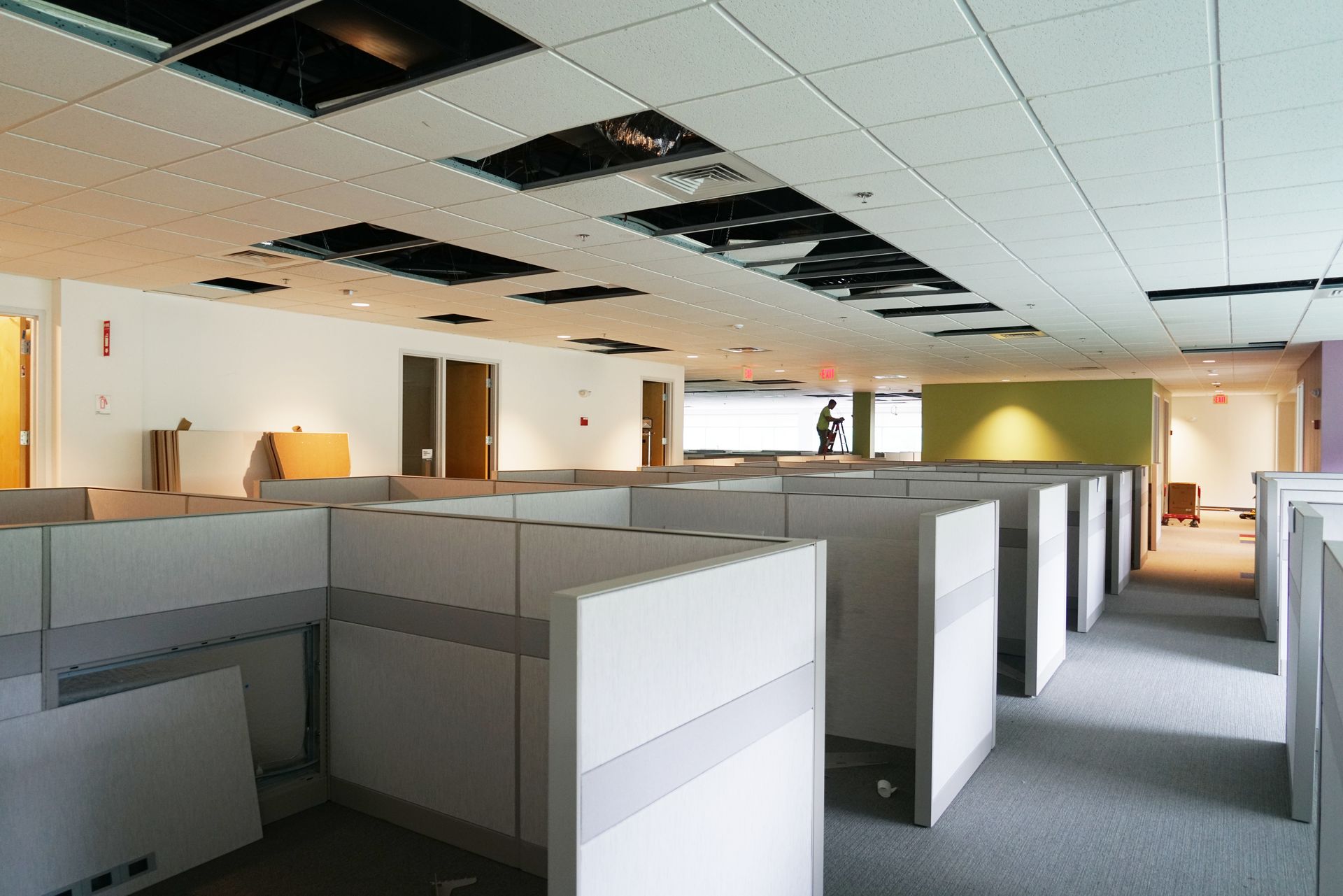 Empty, partitioned office space with missing ceiling tiles showing the infrastructure above.
