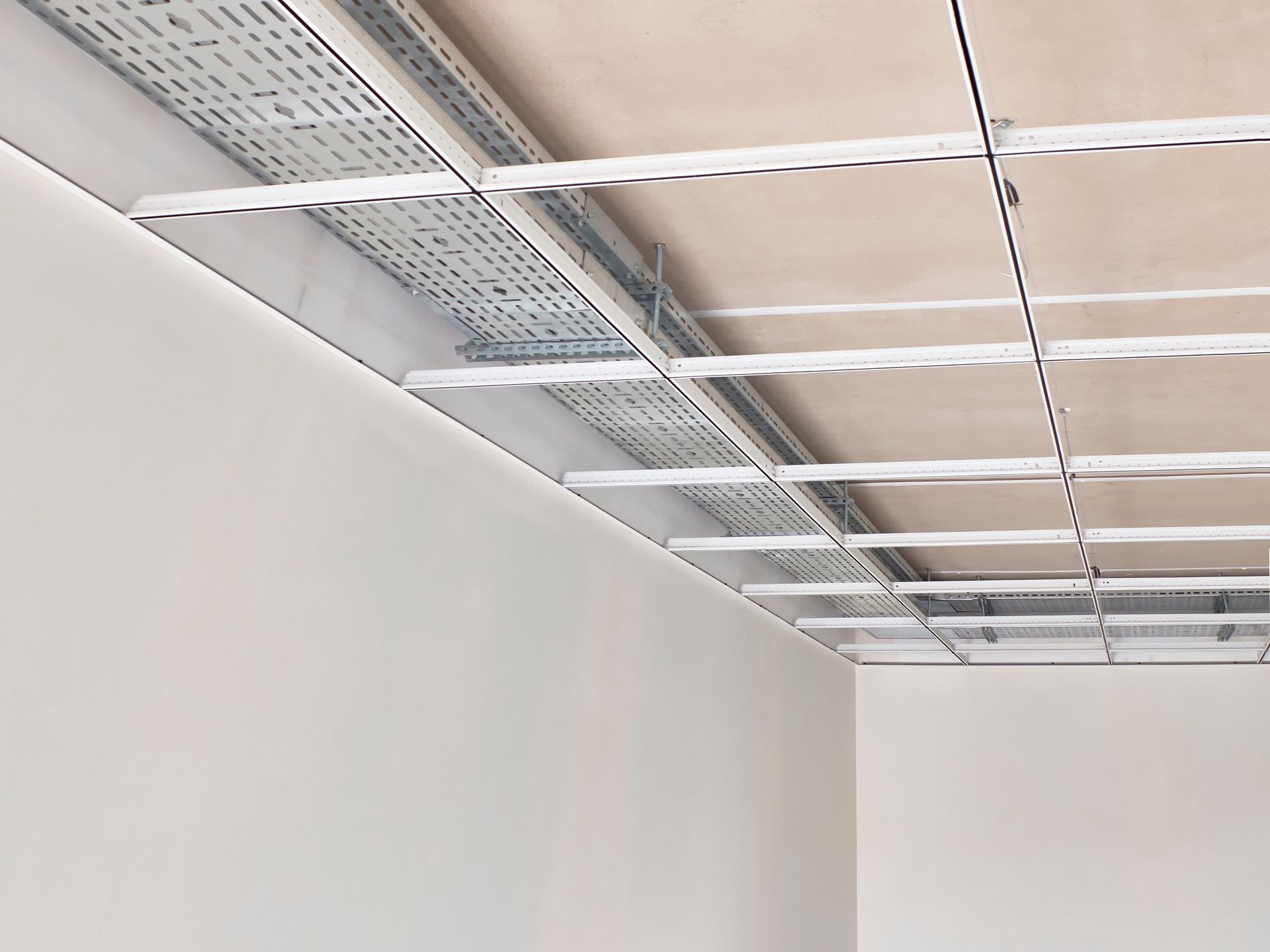A metal cable tray installed along the corner of a ceiling, integrated with a white suspended grid framework.