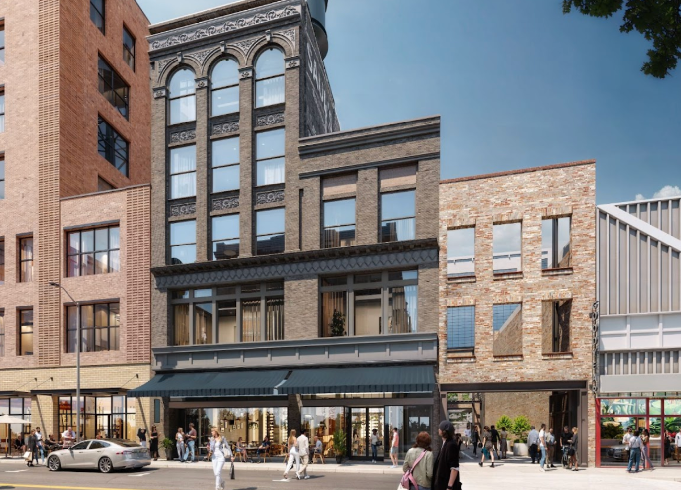 Street-level view of a historic brick building with storefronts and pedestrians on a sunny day