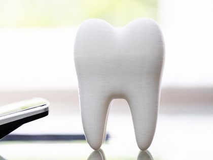 A tooth is sitting on a table next to a calculator.