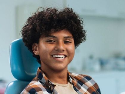 A young man is sitting in a dental chair and smiling.