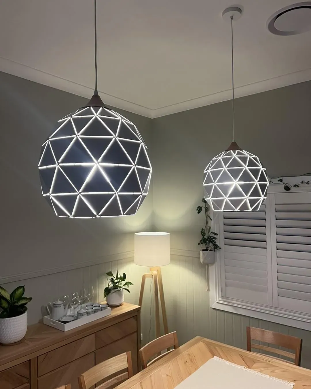 Two Geometric Pendant Lights Illuminate a Dining Room With Plants and a Wooden Table — Forster Solar and Lighting In Forster, NSW
