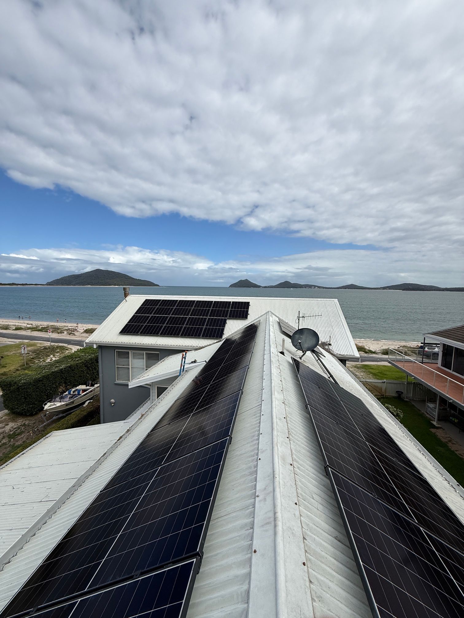 Solar Panels on a Rooftop Against a Background of Trees and Blue Sky — Forster Solar and Lighting In Forster, NSW